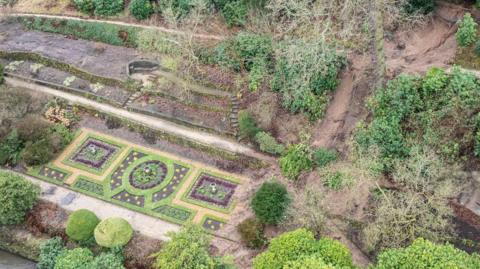 Drone shot of a large landslide which has fallen across the previously intricately designed gardens.