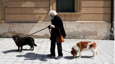 Woman walks her dogs in Locri, Calabria region, southern Italy - 8 April