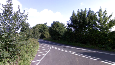 A junction on Burnett Hill with the road lined by hedgerows
