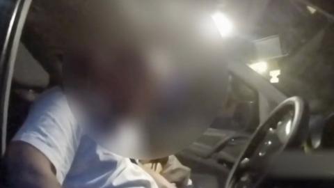 Man behind the wheel, his face is heavily blurred.