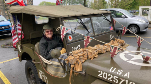 A woman in a World War Two Jeep decorated with bunting.