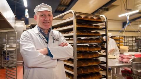 Andrew Chisholm, owner of Christie's the Baker, standing next to bread rolls