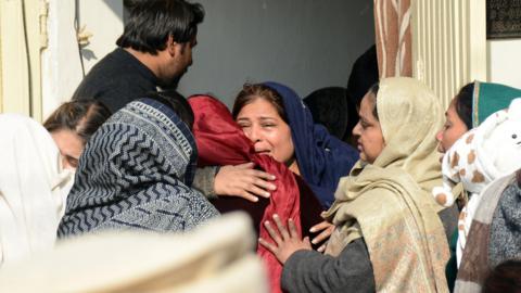 Mourners react after the death of their relatives following a powerful gas cylinder explosion at a wedding function in a neighborhood of Islamabad on January 11, 2026