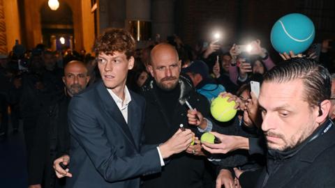 Jannik Sinner signs tennis balls on his way into the ATP Finals venue in Turin