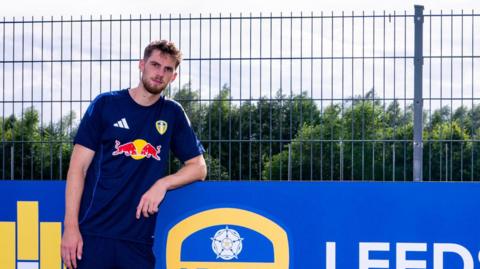 Anton Stach standing beside a Leeds United sign
