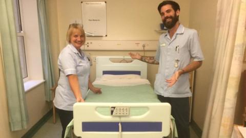 Nursing staff standing either side of a new hospital bed
