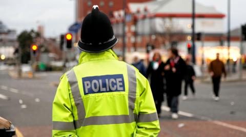 A police officer seen from behind with a bright yellow jacket 