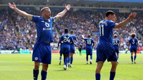 Jamie Vardy stands with his arms raised on the pitch at the King Power Stadium in Leicester
