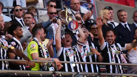 Notts Count captain Matt Palmer lifts the trophy with team-mates following promotion after the Sky Bet League Two play-off final at Wembley Stadium, London.