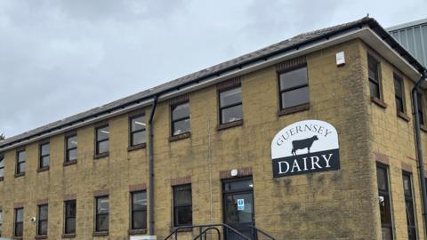 A view of the outside of the dairt. It is a building constructed or light yellow bricks