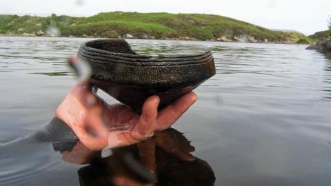 Diver's hand holding Neolithic pottery