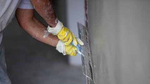 A generic shot of a plasterer plastering a wall using a large trowel