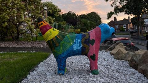 A side view of the multicoloured painted Superlambanana sculpture