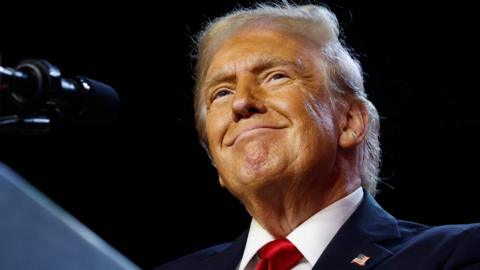 Donald Trump close up in dark suit, white shirt and red tie