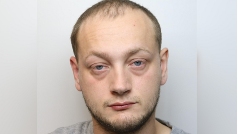 A police custody image of Reece Jolliffe. He has short dark hair and a small amount of facial hair. 