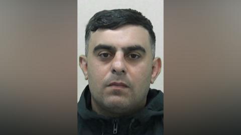 Mugshot of Murad Ibrahim. He has slight dark stubble and short black hair. He is wearing a black zipped hoodie.