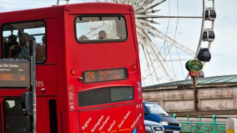 A bus in Brighton with a ferris wheel in the background