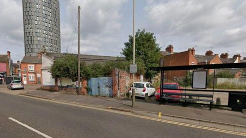 A bus stop in front of a car park and a garage