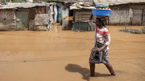 A resident walks through floodwater around homesteads following heavy rains in the Githurai district of Nairobi, Kenya, on Thursday, April 25, 2024.