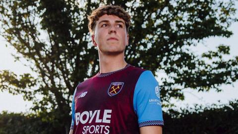 Arne Engels smiles at his unveiling by West Ham as he poses at their training ground after completing his record £22million move from Celtic.