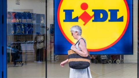 Woman walking past Lidl store