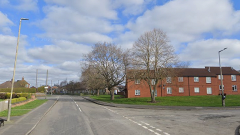 A residential street with red brick council houses on one side
