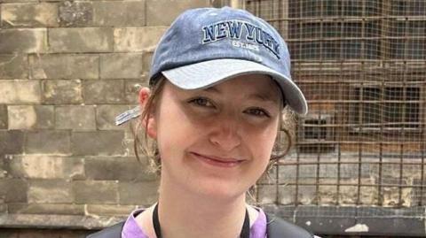 Abigail Eggleston is a young woman who smiling at the camera. Her brown hair is pulled back under a blue cap.