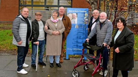 A group of people gathered in front of a blue panel for Don and Doris Connolly.