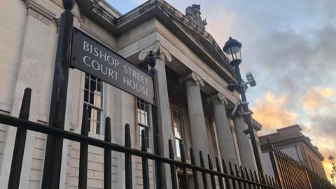 The courthouse in Londonderry with the entrance and sign seen through railings