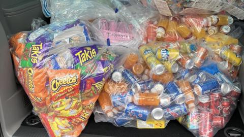 Clear bags containing American Cheetos crisps, Takis, Fanta, Mountain Dew and other drinks which were seized from a shop by Trading Standards.