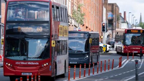 Three buses drive down a road in Birmingham