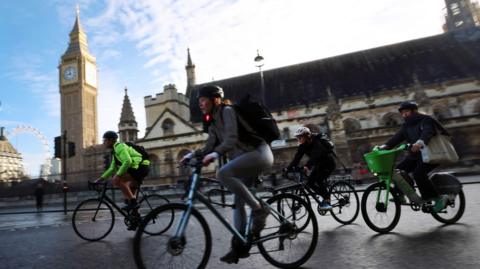 Cyclists ride past Parliament during rush hour in London, on 28 October 2025