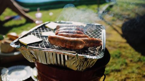 Sausages on a disposable barbecue in a park