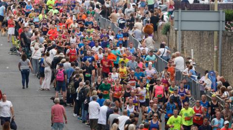 Hundreds of runners, being cheered on by spectators, on the Great North Run track in 2023