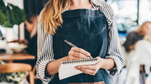 Waitress with pen and paper taking order 