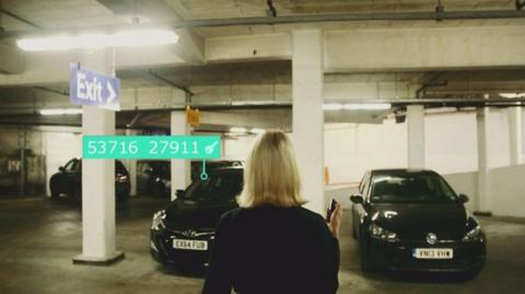 Photo of a blonde haired woman approaching two cars in an underground car park. Overlaid graphics show a line of numbers pointing to one of the cars.
