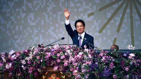 William Lai, in a suit, waves towards the crowd while on stage