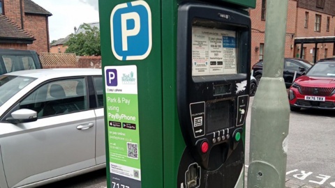 A parking machine with a QR code on the side of it