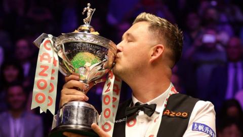 Kyren Wilson celebrates winning the World Championship by kissing the trophy