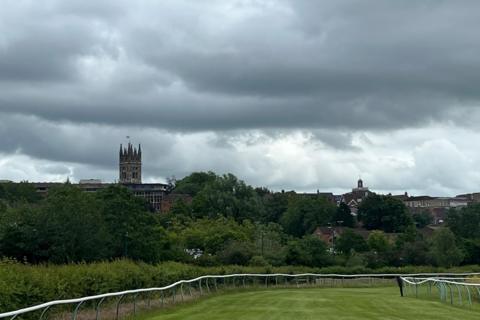 Grassy racecourse under dark storm clouds in Warwick, West Midlands 