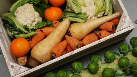 A wooden box filled with fresh vegetables and fruit