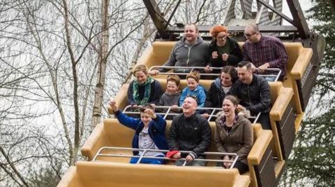 Riders on The Blade can be seen smiling as the ride swings. There are several rows of seats, with safety bars closed over the laps of the people riding.