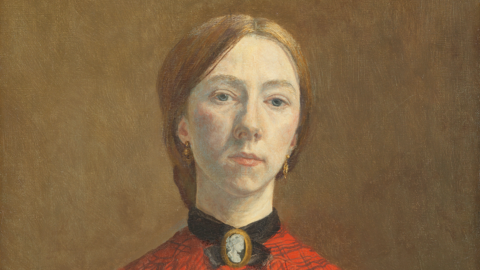 Oil painting of Gwen John. She is a white woman in her twenties. She has light red-brown hair pulled back into a low knot or bun at the back of her head. She is wearing an orange-red blouse with a check pattern on it. at her throat she is wearing a cameo broach with a black ribbon or collar around her throat. The clothing is consistent with the early 1900s.