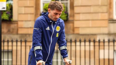 Scotland's Billy Gilmour leaves the team hotel on crutches