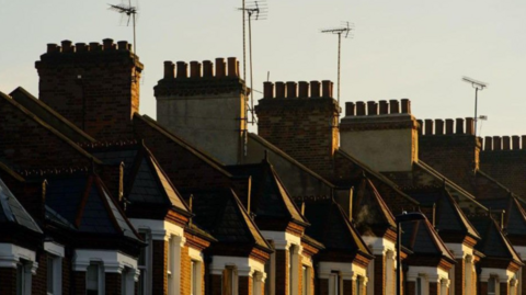 Half a dozen chimneys along with TV aerials are visible above upper floors of properties.