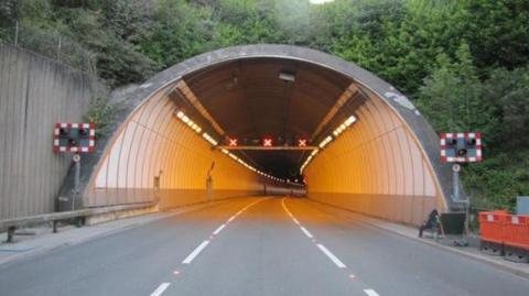 A view of the eastern end of the Saltash tunnel, showing three lanes of empty roads, warning lights and lane control signals