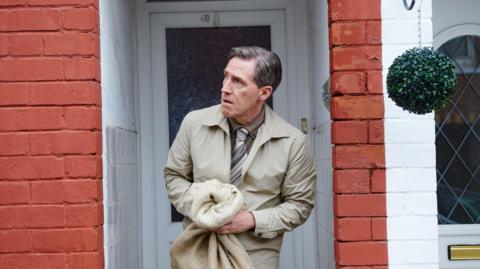 Bryn wearing a white jacket outside his home