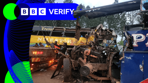 A heavily damaged bus being attached to a tow truck, with a second heavily damaged bus in the background