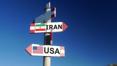 signpost showing Iran and USA directions