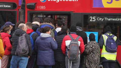 Commuters board buses outside Stratford tube station in London